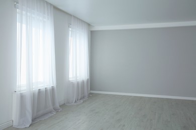 Empty room with large windows and laminated floor