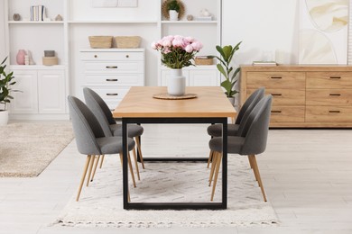 Photo of Stylish dining room with cosy furniture and flowers