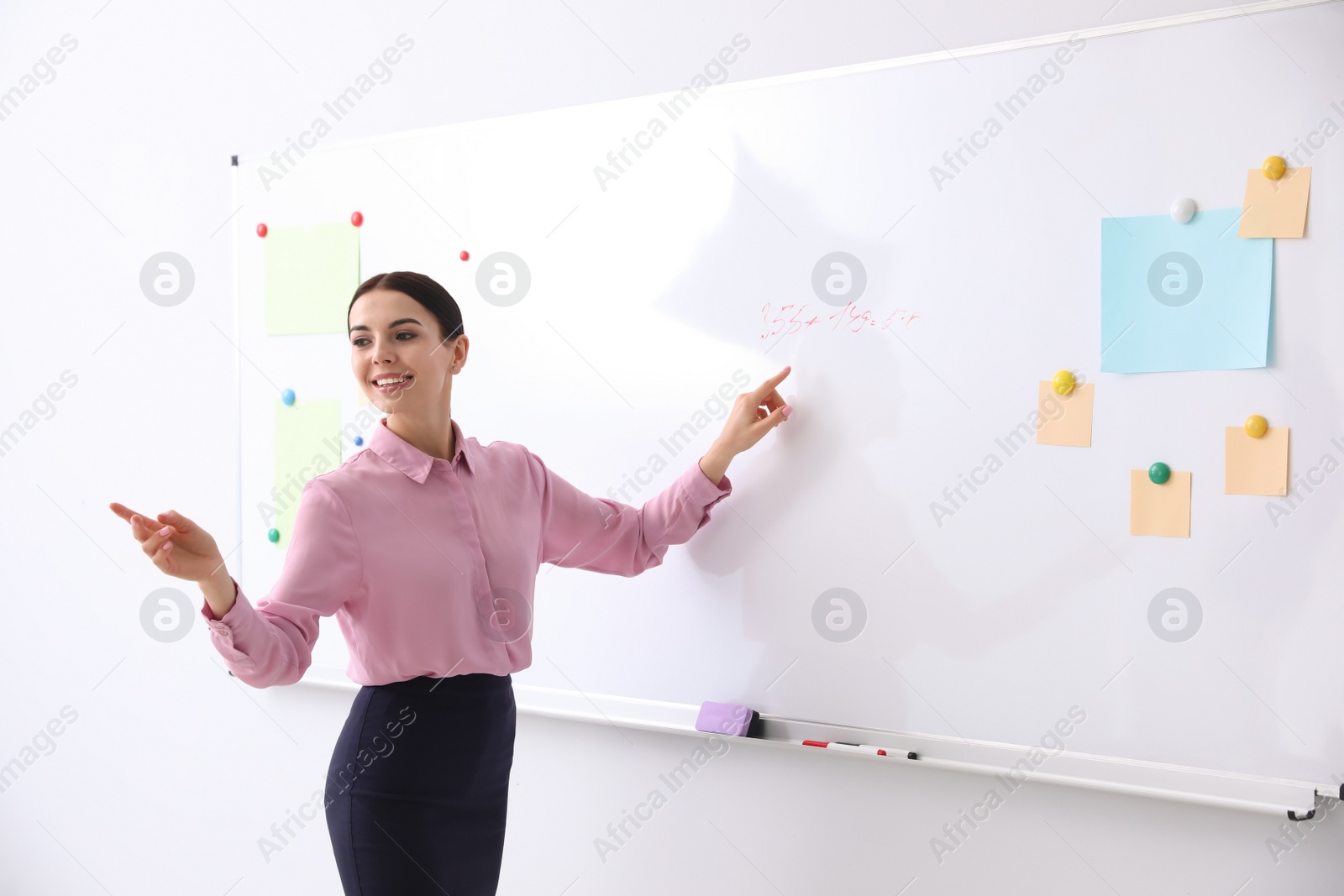 Photo of Young teacher near whiteboard in modern classroom