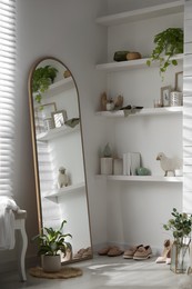 Photo of Different stylish shoes and decorative elements near large mirror in dressing room. Interior design