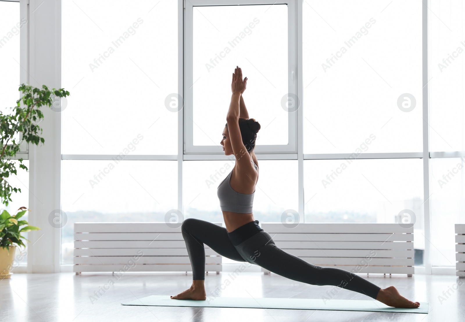 Photo of Young woman practicing crescent pose in yoga studio