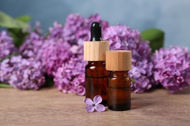 Cosmetic products and lilac flowers on wooden table, space for text