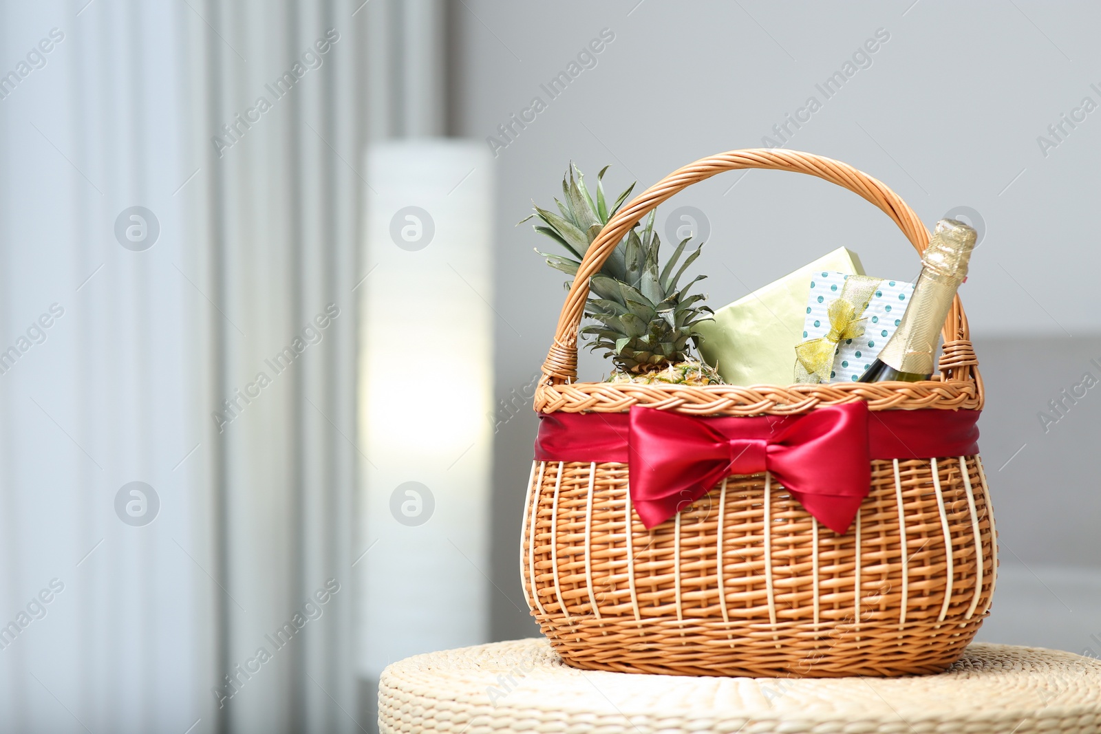 Photo of Wicker basket full of gifts in living room. Space for text