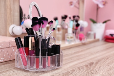 Photo of Organizer with cosmetic products for makeup on table near mirror. Space for text