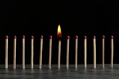 Burning match among others on table against black background. Difference and uniqueness concept