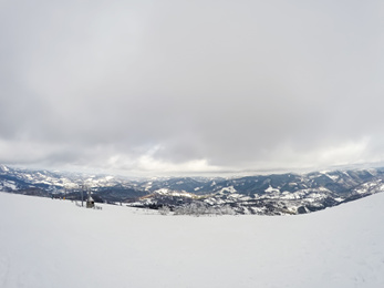 Picturesque view of snowy hill on cloudy winter day. Ski resort