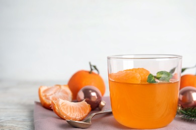 Photo of Delicious tangerine jelly in glass and fresh fruits on table. Space for text