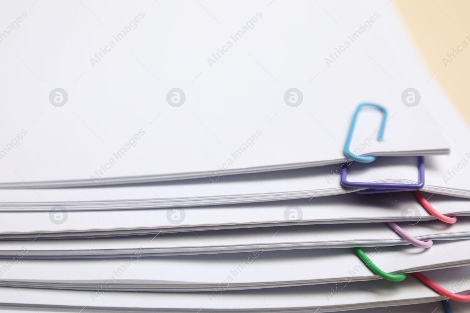 Photo of Sheets of paper with clips on beige background, closeup