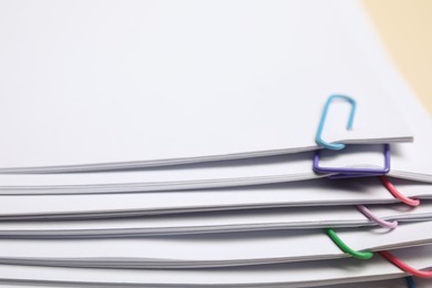 Sheets of paper with clips on beige background, closeup