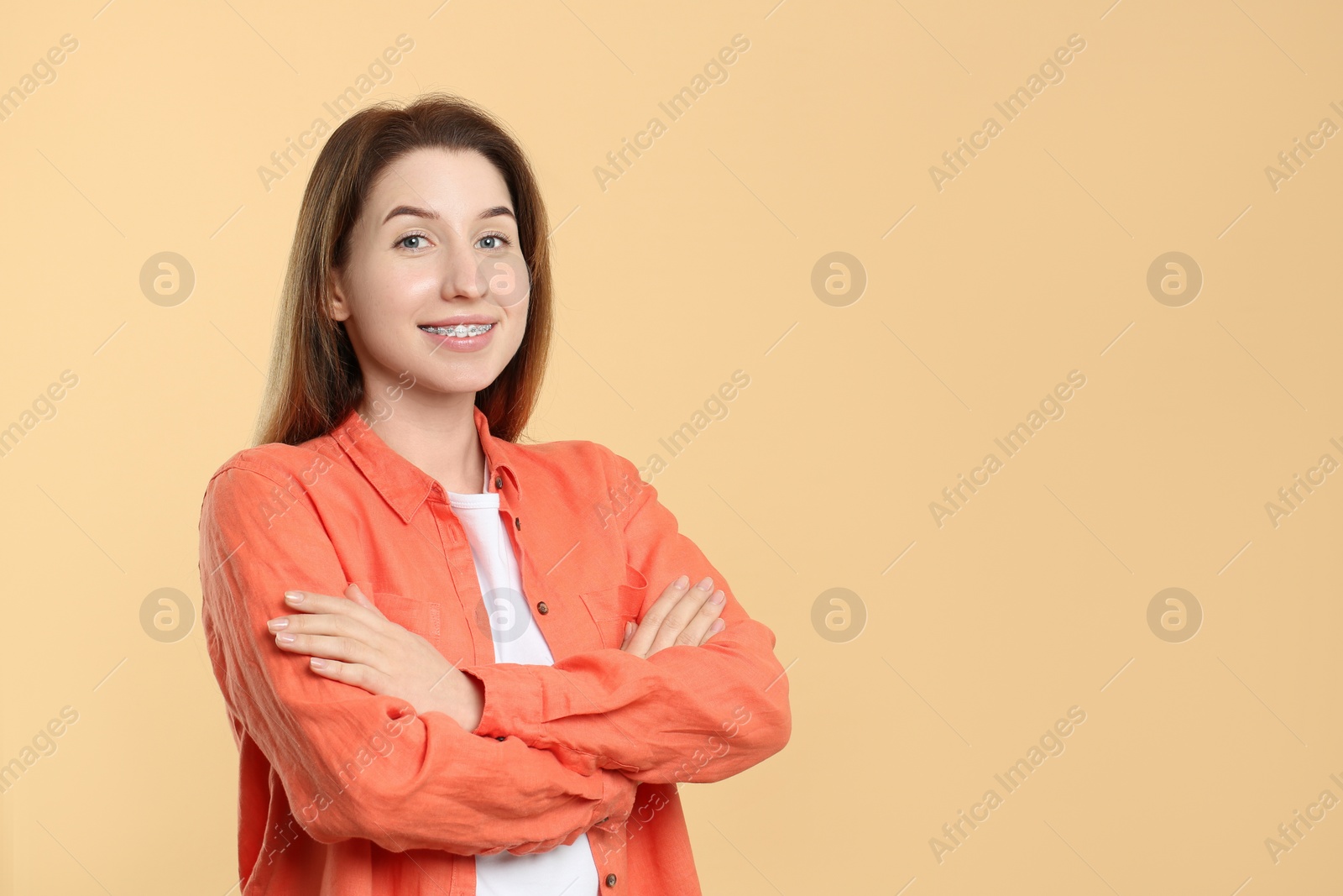 Photo of Portrait of smiling woman with dental braces on beige background. Space for text