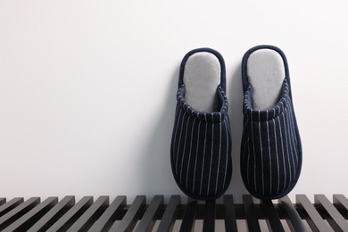 Photo of Pair of stylish slippers on bench against light grey background, space for text