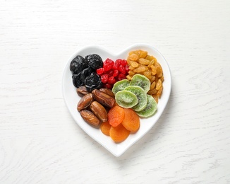 Photo of Plate with different dried fruits on wooden background, top view. Healthy lifestyle