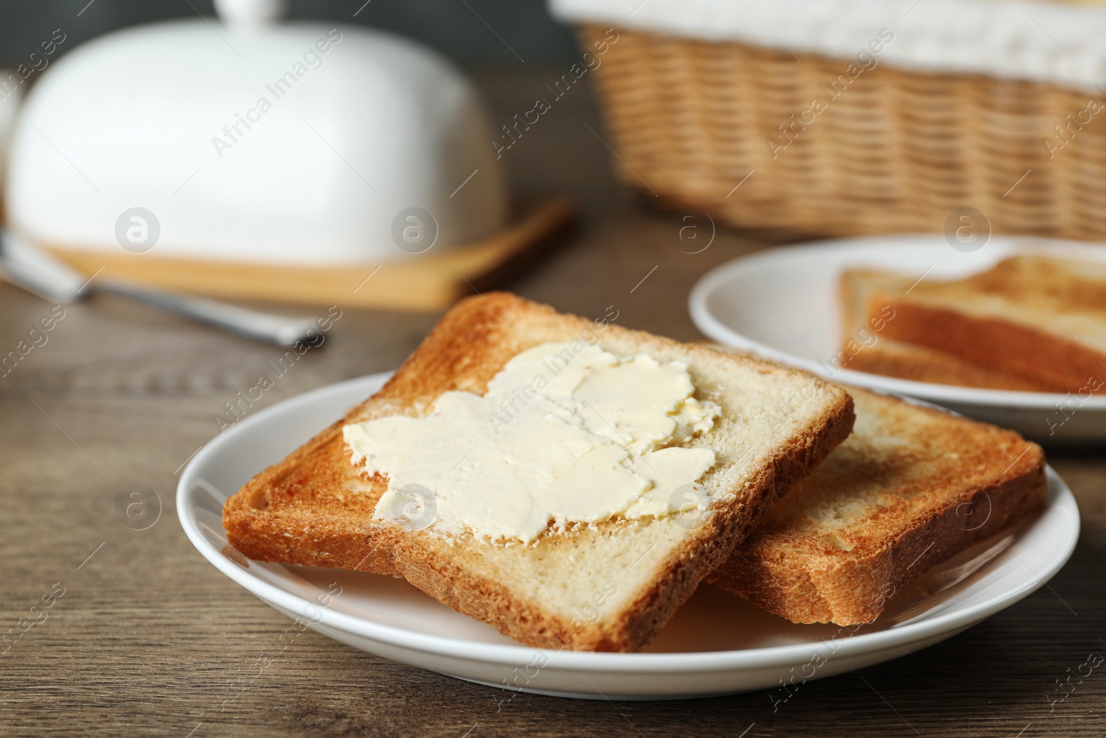 Photo of Crispy toasted bread with butter on wooden table, closeup