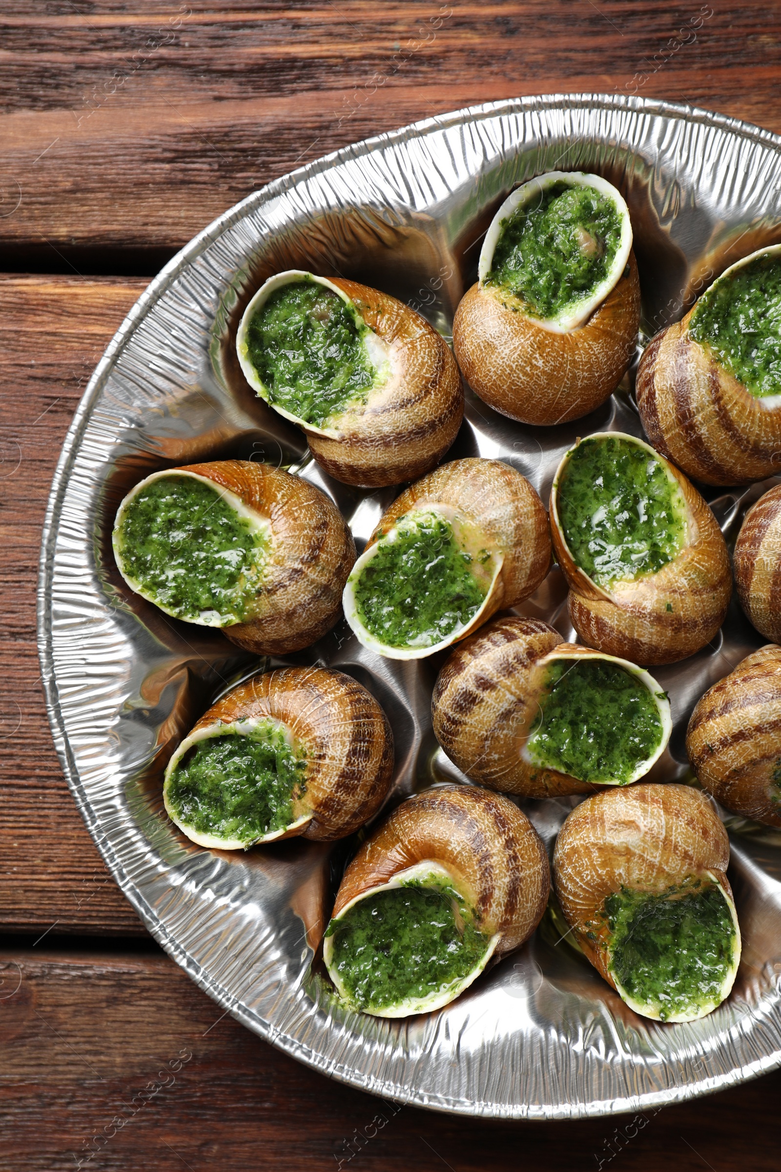 Photo of Delicious cooked snails on wooden table, top view