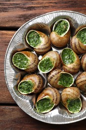 Photo of Delicious cooked snails on wooden table, top view