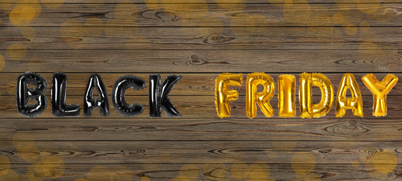 Phrase BLACK FRIDAY made of foil balloon letters on wooden background. Banner design