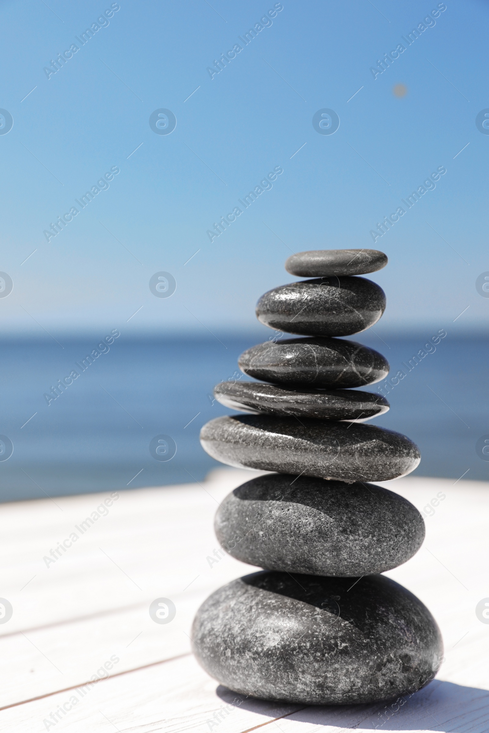 Photo of Stack of stones on wooden pier near sea, space for text. Zen concept