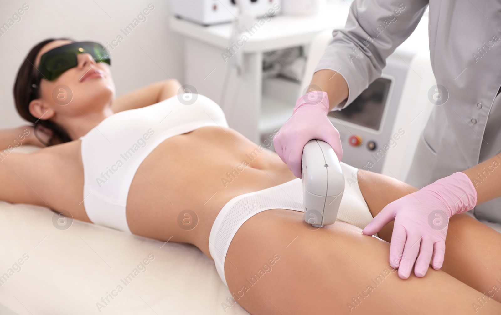 Photo of Young woman undergoing laser epilation procedure in beauty salon