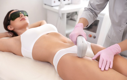 Photo of Young woman undergoing laser epilation procedure in beauty salon