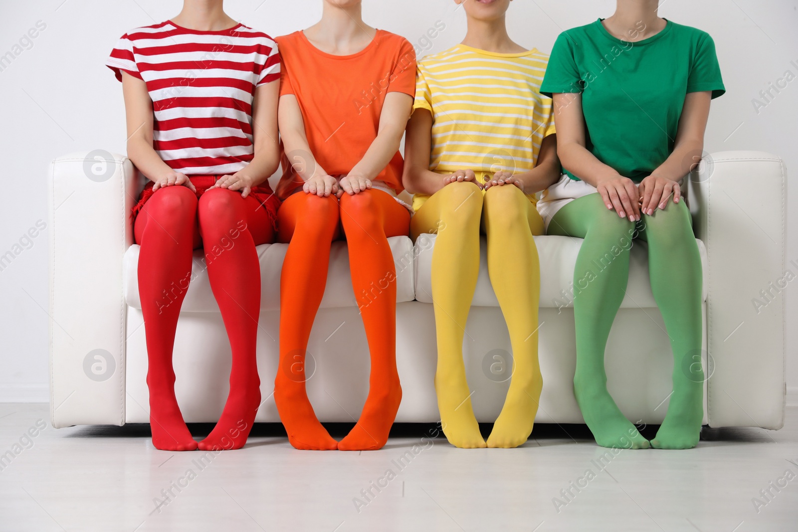 Photo of Women wearing bright tights sitting on sofa indoors, closeup