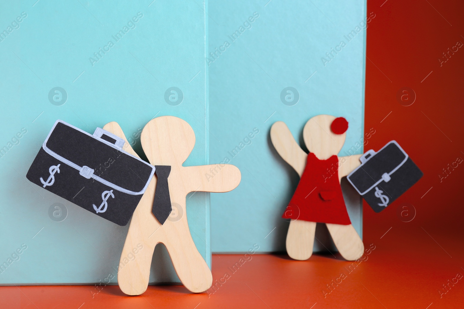 Photo of Gender pay gap. Wooden figures of man and woman with bags on color background