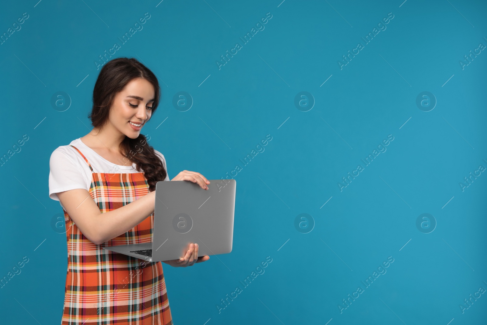 Photo of Young woman with laptop on blue background. Space for text