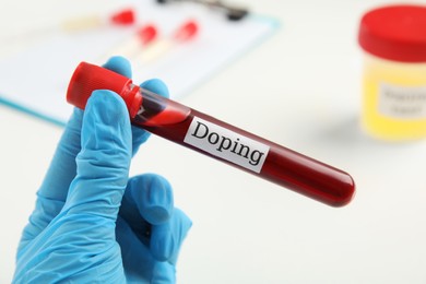 Photo of Doctor holding test tube with blood sample over table, closeup. Doping control