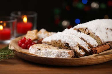Photo of Traditional Christmas Stollen with icing sugar on wooden table, closeup