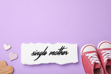 Photo of Being single mother concept. Children's gumshoes and decorative hearts on violet background, flat lay with space for text