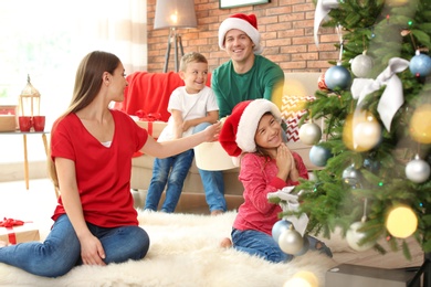 Photo of Happy parents and children decorating Christmas tree together at home