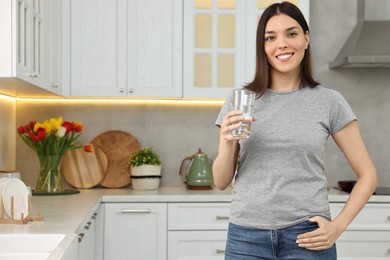 Photo of Woman with glass of fresh water in kitchen