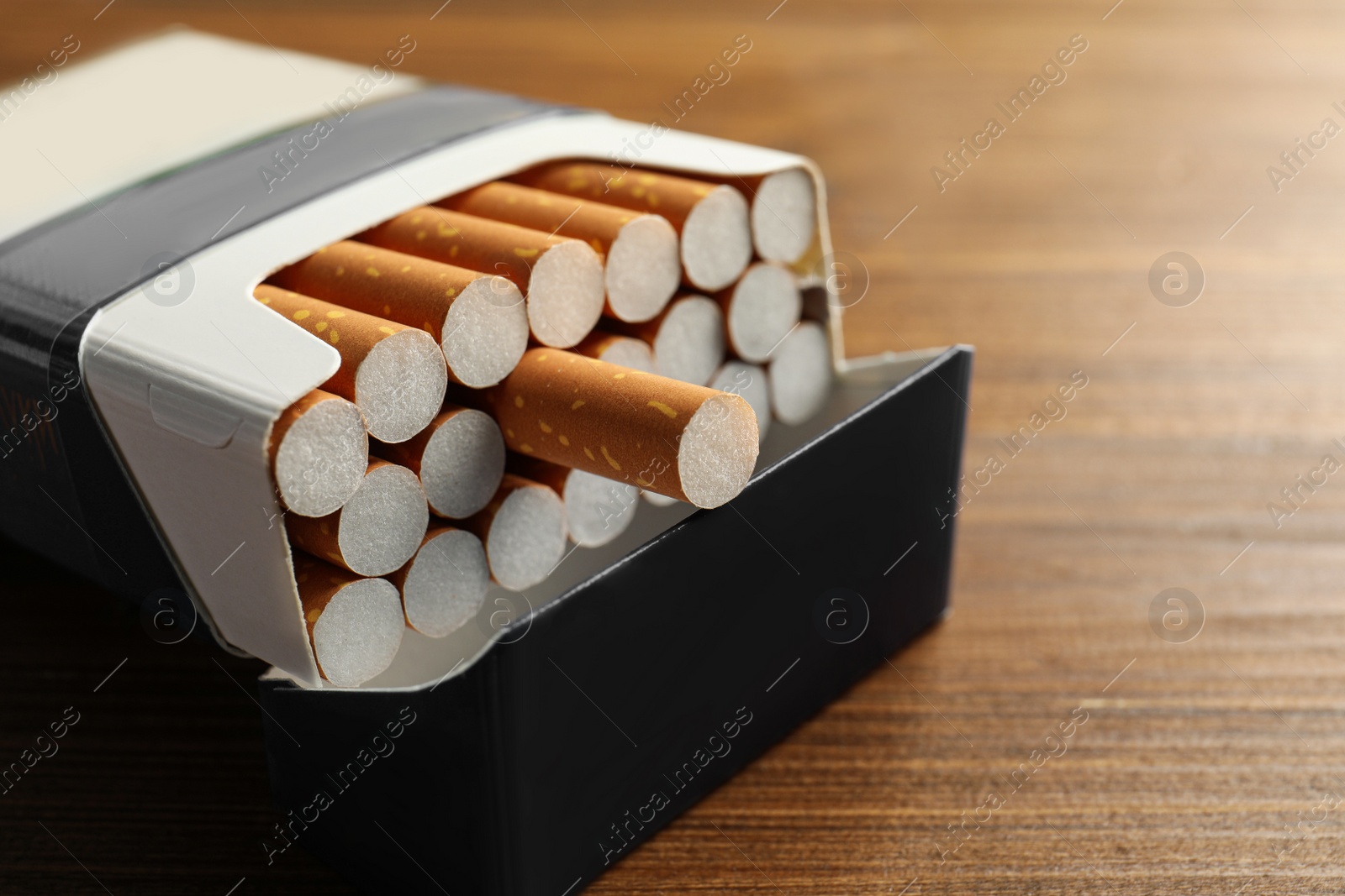 Photo of Pack of cigarettes on wooden table, closeup