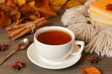 Photo of Composition with cup of hot tea and autumn leaves on wooden table