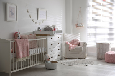Photo of Chest of drawers with changing tray and pad in baby room. Interior design