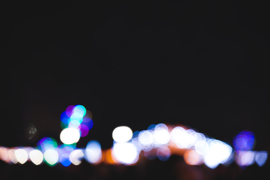 Photo of Blurred view of city street with festive lights at night. Bokeh effect