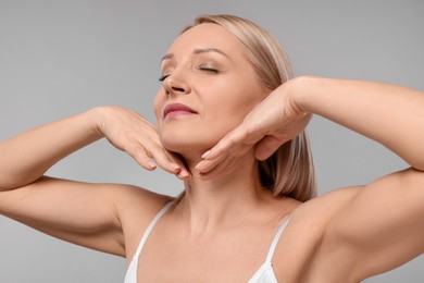 Photo of Beautiful woman touching her neck on grey background