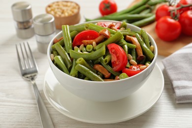 Photo of Delicious salad with green beans, mushrooms, pine nuts and tomatoes served on white wooden table