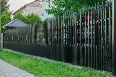 Photo of Beautiful black iron fence near pathway outdoors