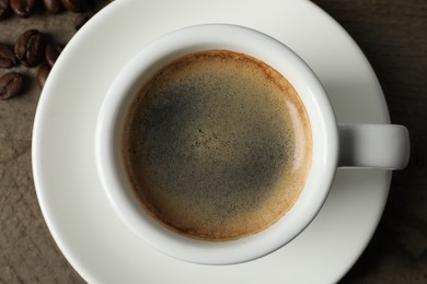 Photo of Cup of aromatic coffee on wooden table, top view