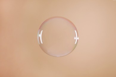 Photo of One beautiful soap bubble on light brown background