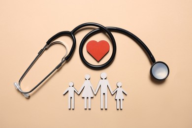 Photo of Figures of family, stethoscope and heart on beige background, flat lay. Insurance concept
