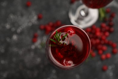 Photo of Tasty cranberry cocktail with rosemary in glass on gray table, top view