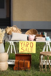 Photo of Table with different stuff and sign Yard sale outdoors