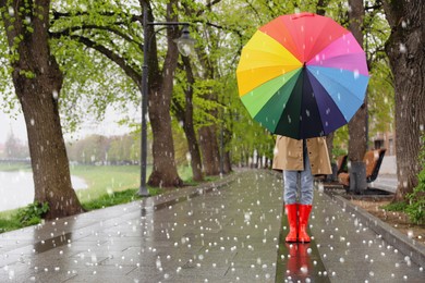 Image of Young woman with umbrella walking in park on rainy day with hail