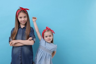 Cute little sisters on light blue background, space for text