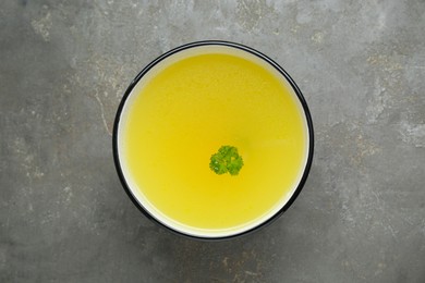 Photo of Delicious chicken bouillon with parsley on grey table, top view