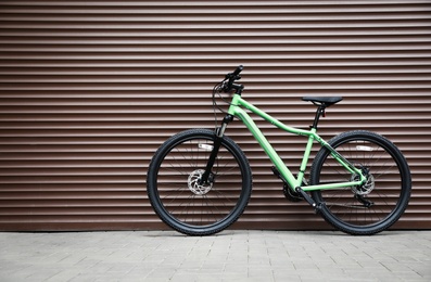 Photo of New modern color bicycle near brown wall outdoors