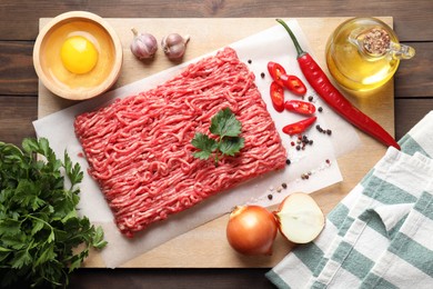 Photo of Raw ground meat and different products on wooden table, flat lay