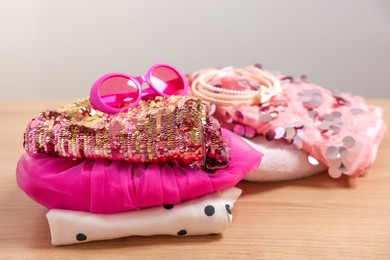 Photo of Stylish carnival costume with sequins, sunglasses and headbands on wooden table