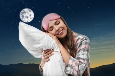 Image of Beautiful woman holding pillow and night starry sky with full moon on background. Bedtime